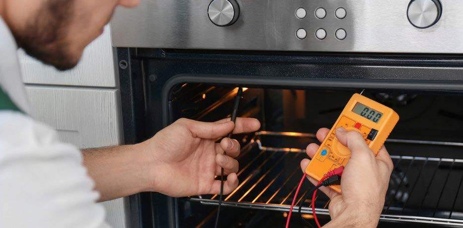 Major Appliance Service- Technician using a multimeter with red and black probes to measure voltage on a part